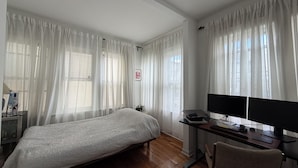 Een slaapkamer met een bed, een bureau met een computer en een stoel.