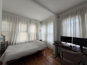 Ein Schlafzimmer mit einem Bett, einem Schreibtisch mit Computer und einem Sessel.