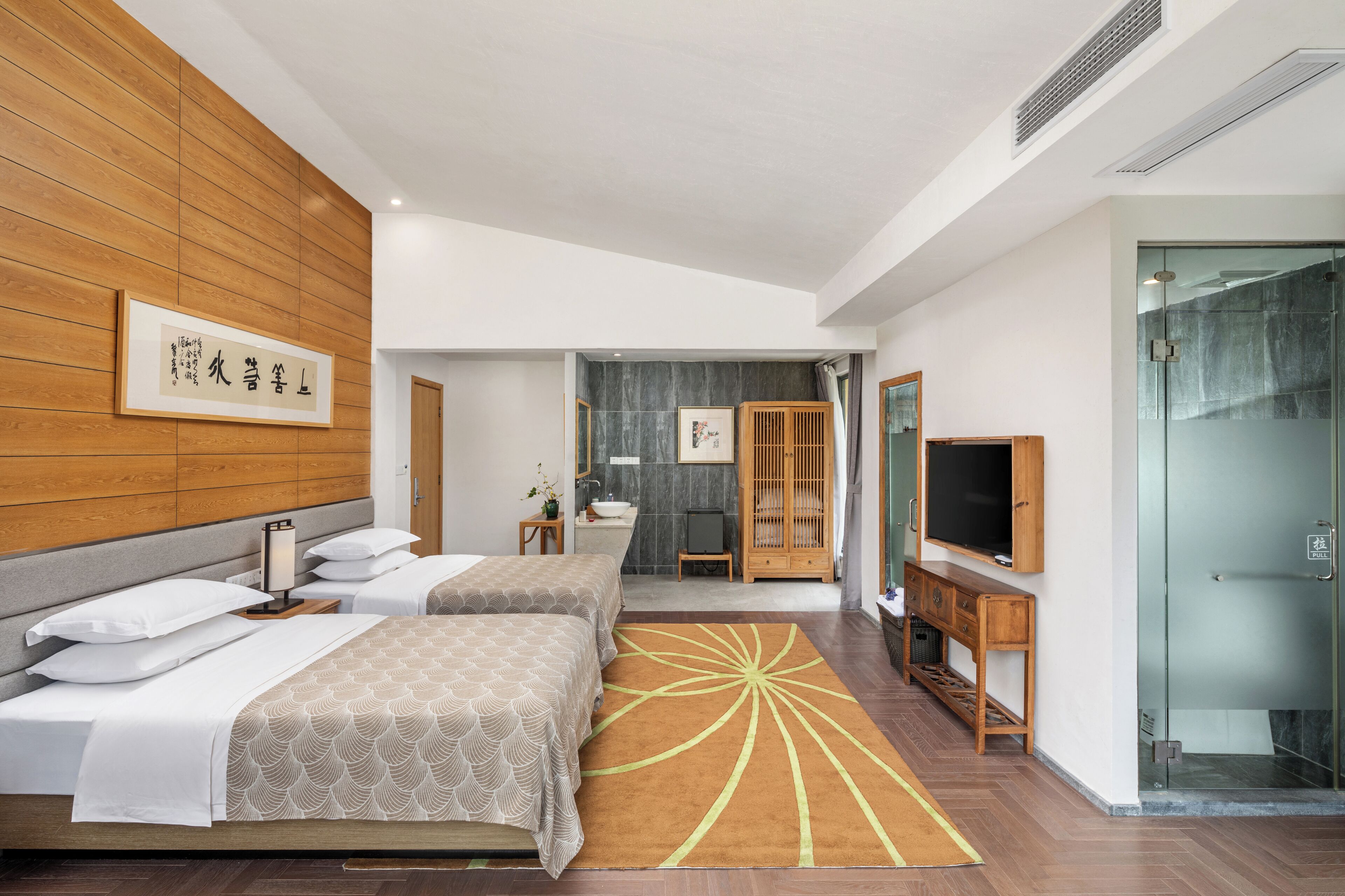 Una habitación de hotel moderna con dos camas, un televisor, un baño y zona de ducha.