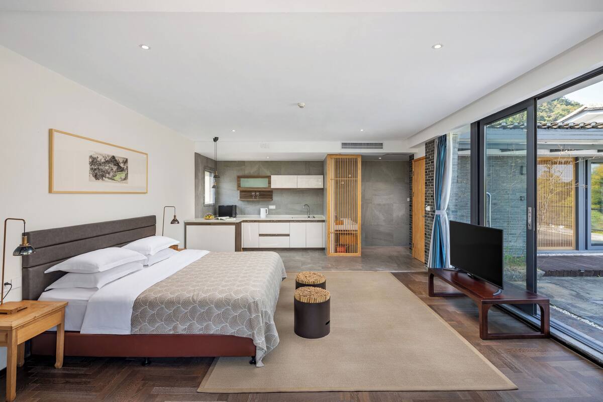 A modern bedroom with a bed, bedside table, and a TV stand with a flat-screen TV.
