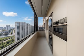 Un balcón con vistas a edificios de la ciudad, una lavadora y un microondas.