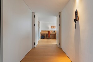 A hallway leading to a kitchen with a wooden floor, white walls, and a modern light fixture. - Chengyu B&B-Loft view suite (Zhangjiajie)