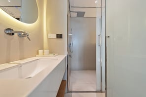 Un baño moderno con una bañera grande, cabina de ducha con paredes de vidrio y un espejo fijado a la pared.