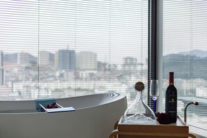 A modern bathroom with a bathtub, a wine bottle, and a vase on a tray. - Chengyu B&B-Loft view suite (Zhangjiajie)