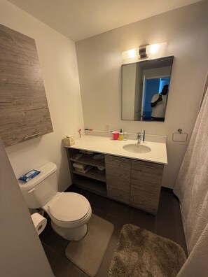 A bathroom with a toilet, sink, mirror, and a shower curtain.