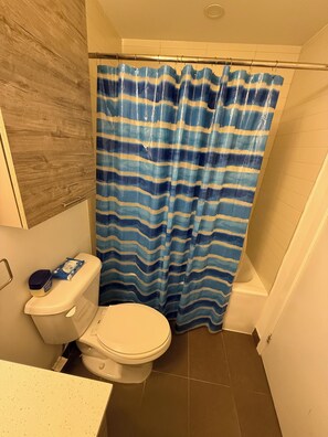 A bathroom with a striped shower curtain, a toilet, and a sink.