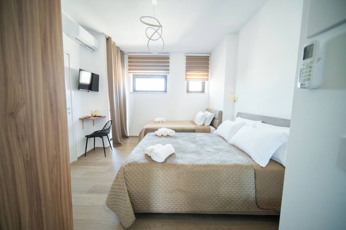A hotel room with two beds, a TV, a desk, and a chair.