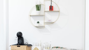 A wooden cabinet with drawers, a small shelf with plants, and a round mirror on the wall. - Newhouse ARGIRO Deluxe (Bari)