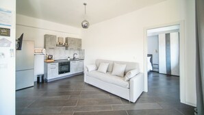 A modern kitchen with a white countertop, built-in oven, and a hanging light fixture. - Newhouse ARGIRO Deluxe (Bari)