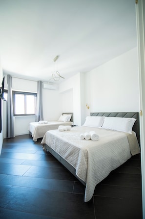 Habitació d'hotel amb dos llits, un gran finestral i un terra negre.