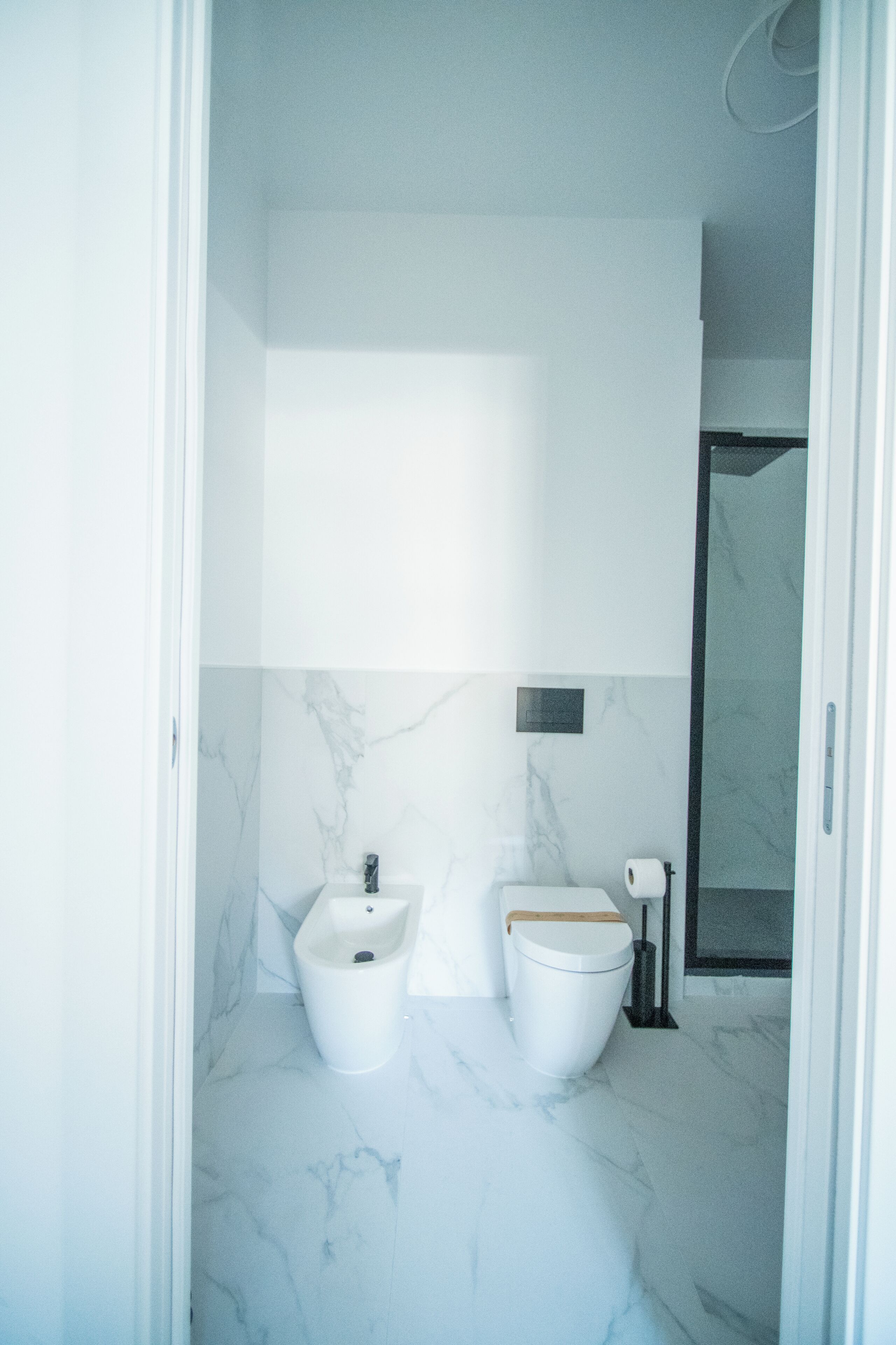 Un bagno con pavimento in marmo, bidet, WC e zona doccia.