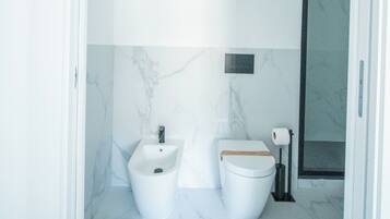 Un bagno con pavimento in marmo, bidet, WC e zona doccia.
