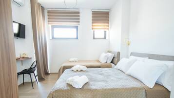 A hotel room with two beds, a desk, a chair, a TV, and a window with curtains.