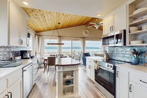 Eine moderne Küche mit Holzbalkendecke, eingebauten Geräten und Bergblick.