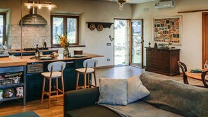 Eine moderne Küche mit Kochinsel, Barhocker und einem Essbereich mit Sofa und Stühlen.