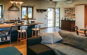 A modern kitchen with a central island, bar stools, and a dining area with a sofa and chairs. - Casa Vacanze Monte Amiata (Stribugliano)