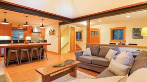 A spacious living area with a kitchen, a sofa, and a coffee table. - The Shuksan | Hot Tub + Game Room + Pool (Deming)