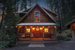 A wooden cabin with a porch, two windows, and a sign above the door.