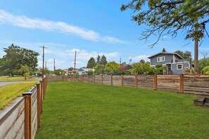 A fenced yard with a grassy area, a wooden fence, and a house with a blue roof. - World Cup 2026 3BR. Near downtown Seattle attractions. Modern living space (Seattle)