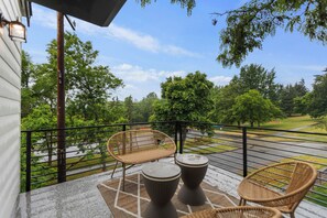 A balcony with wicker furniture, a view of a golf course, and a clear sky. - World Cup 2026 3BR. Near downtown Seattle attractions. Modern living space (Seattle)