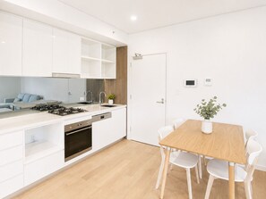 Eine moderne Küche mit weißen Schränken, einem Holztisch und weißen Stühlen.