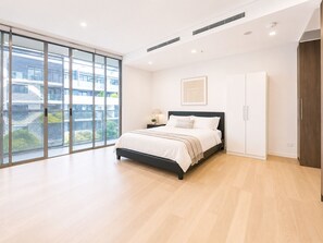 Ein modernes Schlafzimmer mit großem Fenster, einem Bett, einem Kleiderschrank und einem Nachttisch.
