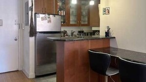 Une cuisine moderne avec des meubles en bois, un réfrigérateur en acier inoxydable et un coin bar équipé de deux tabourets.