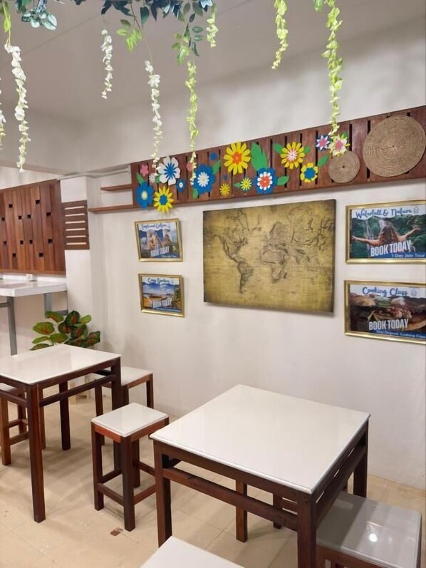A room with wooden tables and chairs, a world map on the wall, and various framed pictures.