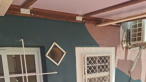 Una stanza con una porta bianca, una finestra con inferriata in metallo e un muro con finitura strutturata.