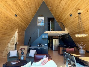 A spacious loft-style room with a wooden ceiling, a staircase to an upper level, a dining area, and a kitchen.