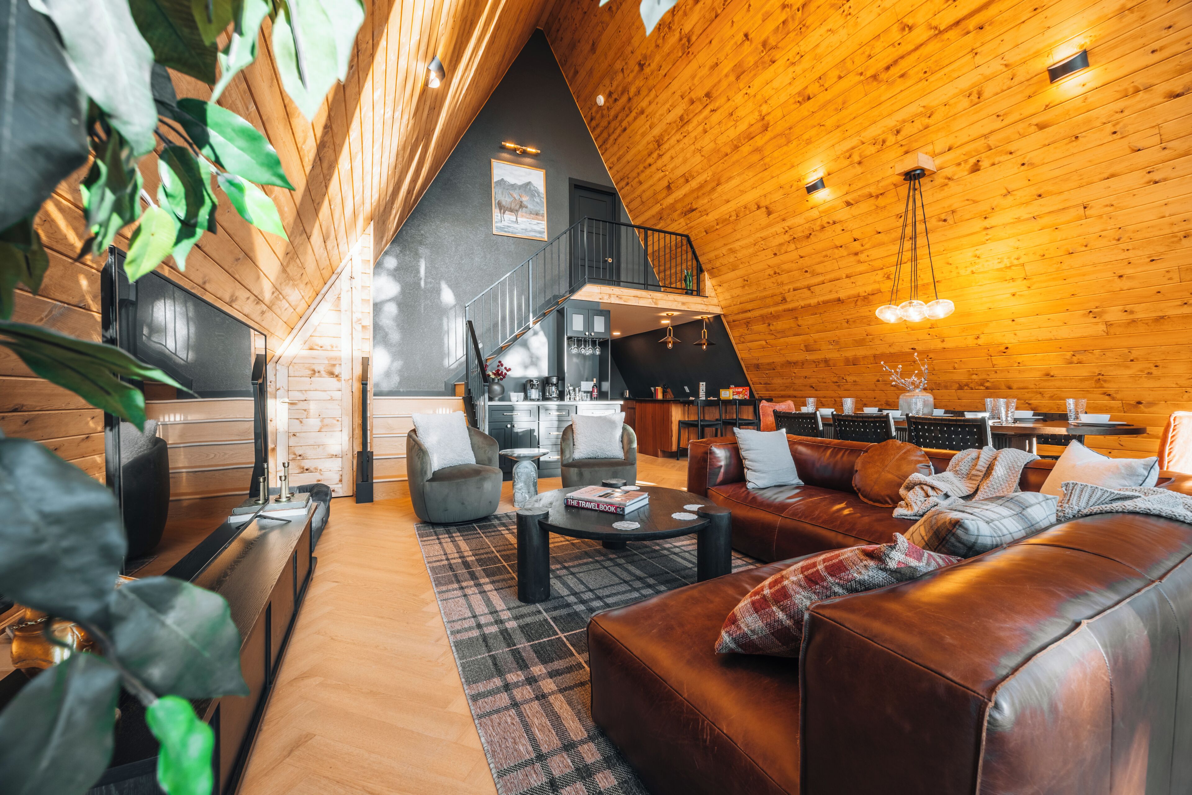 A spacious loft-style living area with a high ceiling, wooden beams, a fireplace, and a cozy seating arrangement.