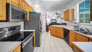 A modern kitchen with stainless steel appliances, wooden cabinets, and a large window.