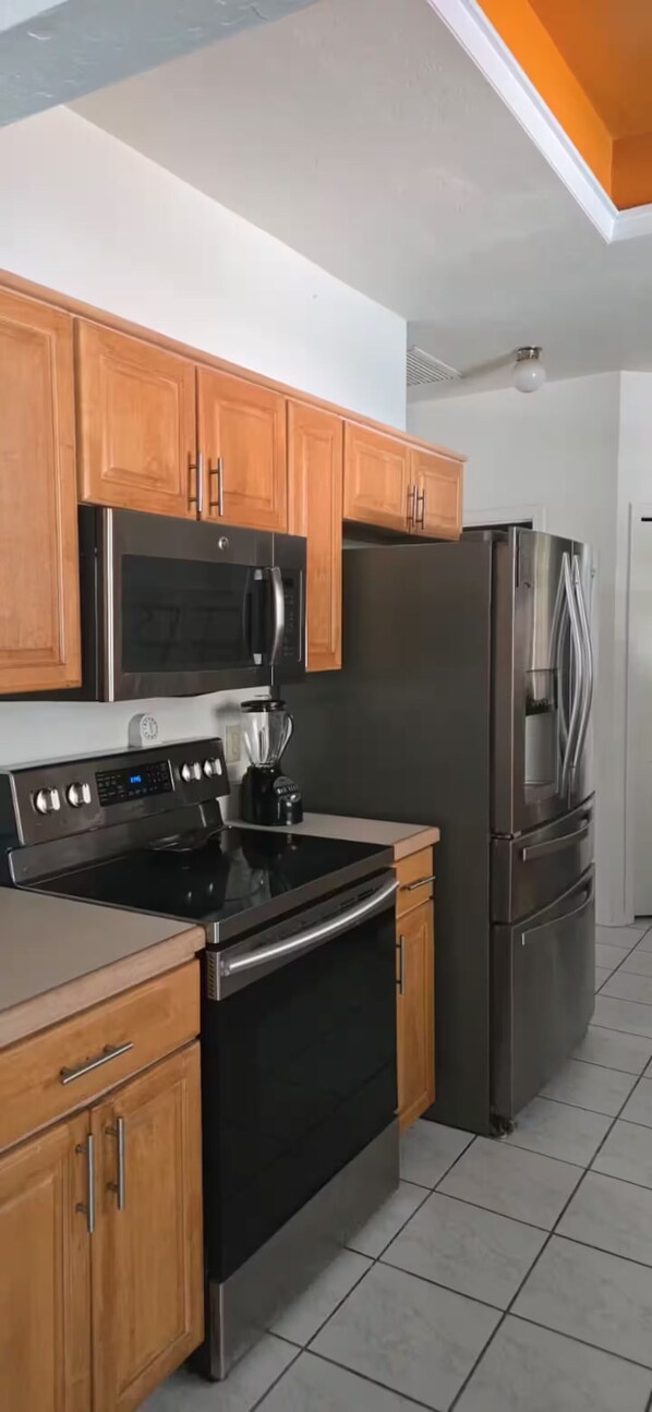 Una cocina con armarios de madera, una estufa de acero inoxidable, un microondas y un refrigerador.