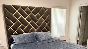 A bed with a tufted headboard, a grey bedspread, and a wooden frame.