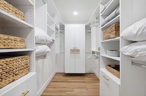 A narrow walk-through closet with white shelving, baskets, and a central door labeled 'Owner's Closet.'