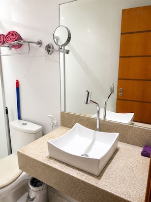 A bathroom with a white sink, a mirror, a towel rack, and a toilet.