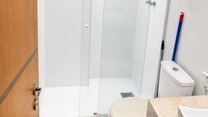 Een badkamer met douche, toilet en wastafel.