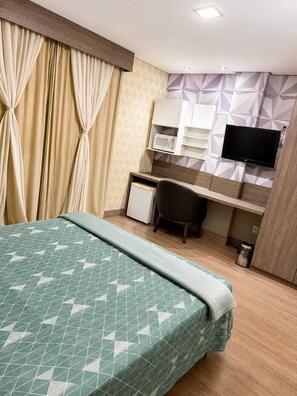A hotel room with a bed, a desk, a chair, a television, and a microwave. - Vrbo Property (nova iguacu)