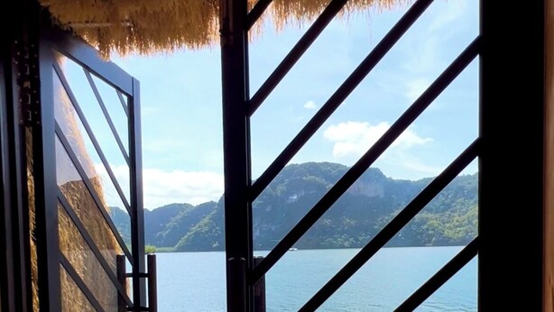 Puerta de madera que da a una terraza con vistas a un lago y montañas.