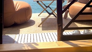Una habitación con vistas a un lago y montañas, una mesa con cafetera y dos sillones tipo bean bag.