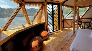 Interior de madera con una cama, zona de estar y vistas a un lago.