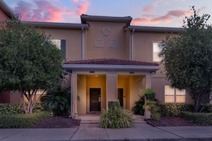 A building with a symmetrical facade, a central entrance with double doors, and a tiled roof. - Welcoming Townhome 4BD3BA at Paradise Palms PP8955 (Kissimmee)