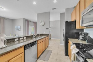 A modern kitchen with a dishwasher, stove, refrigerator, and wooden cabinets. - Welcoming Townhome 4BD3BA at Paradise Palms PP8955 (Kissimmee)