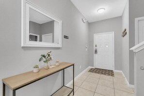 A hallway with a white door, a console table with a mirror, and a small plant. - Welcoming Townhome 4BD3BA at Paradise Palms PP8955 (Kissimmee)