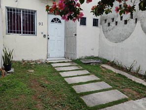 A white building with a number '91' on the door, a gated entrance, and a stone pathway leading to the door. - NICE VIEW HOUSE IN CANCUN (CANCUN)