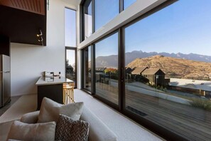 A modern interior with large windows, a kitchen area, and a view of mountains. - Stone Ridge: Modern House with Lake Views (Queenstown)