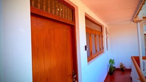 A hallway with a wooden door and window, a staircase, and potted plants.