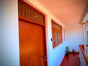 A hallway with a wooden door and window, a staircase, and potted plants.
