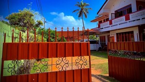 A gated property with a red fence, a white building with balconies, and a palm tree in the background.