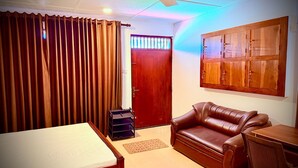 A room with a bed, a leather sofa, a wooden desk, a ceiling fan, and a wardrobe.